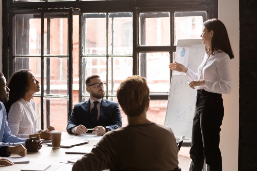 אישה מציגה מצגת בישיבת עובדים.